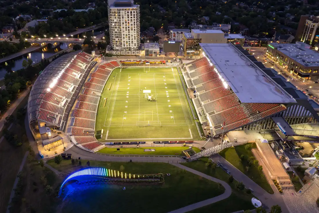 TD Place lit at night from above, with Lansdowne Park and the Rideau Canal around it