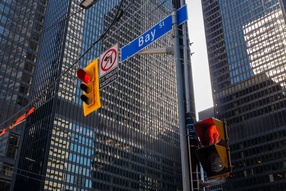 A Bay Street sign and a red traffic light in front of bank towers in Toronto’s financial district